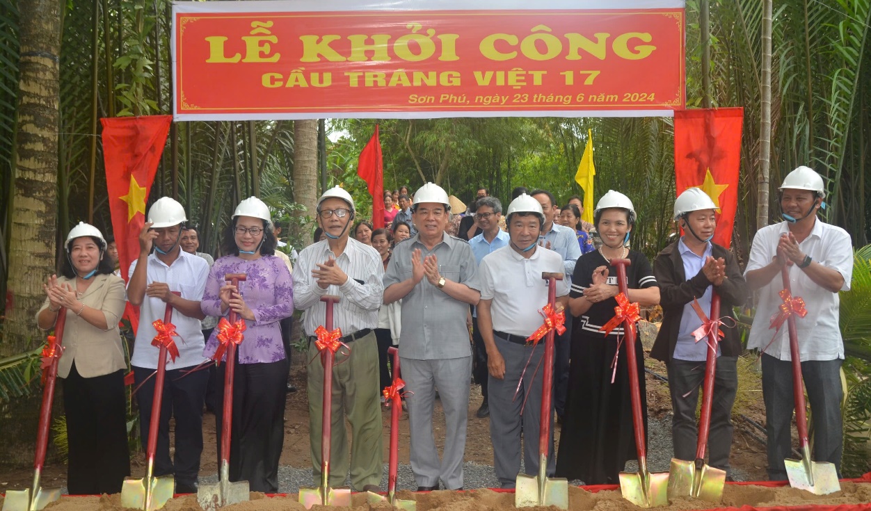 A group of people standing under a sign Description automatically generated