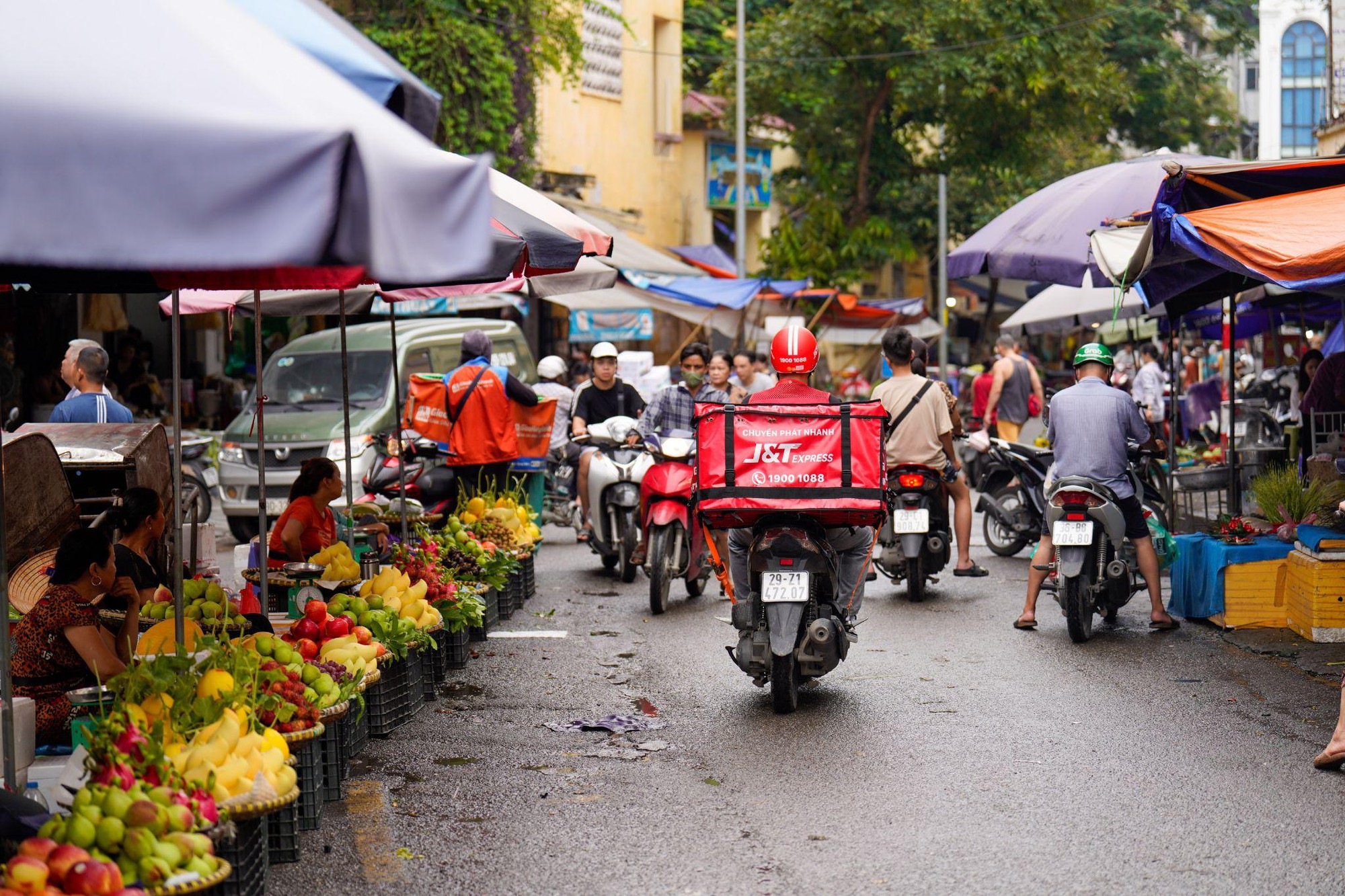 A group of people on motorcycles and fruit stand  Description automatically generated