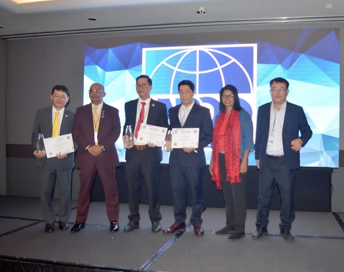 A group of people standing on a stage holding certificates  Description automatically generated
