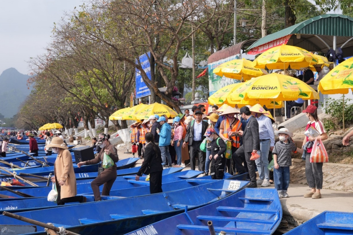 A group of people standing next to boats  Description automatically generated