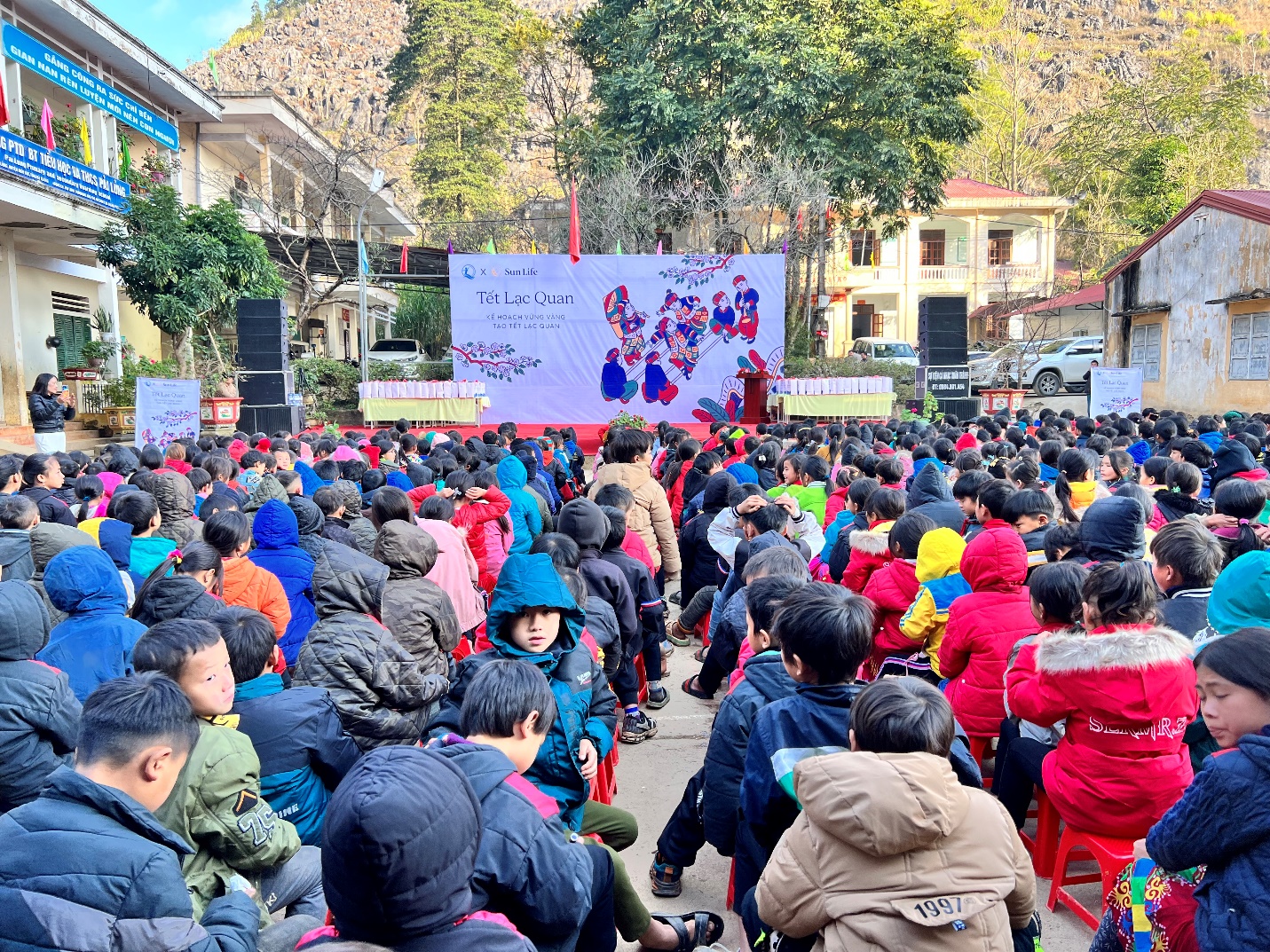 A group of children sitting in chairs in front of a stage  Description automatically generated