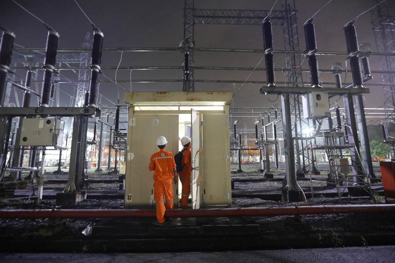 Men in orange jumpsuits standing in a power plant Description automatically generated