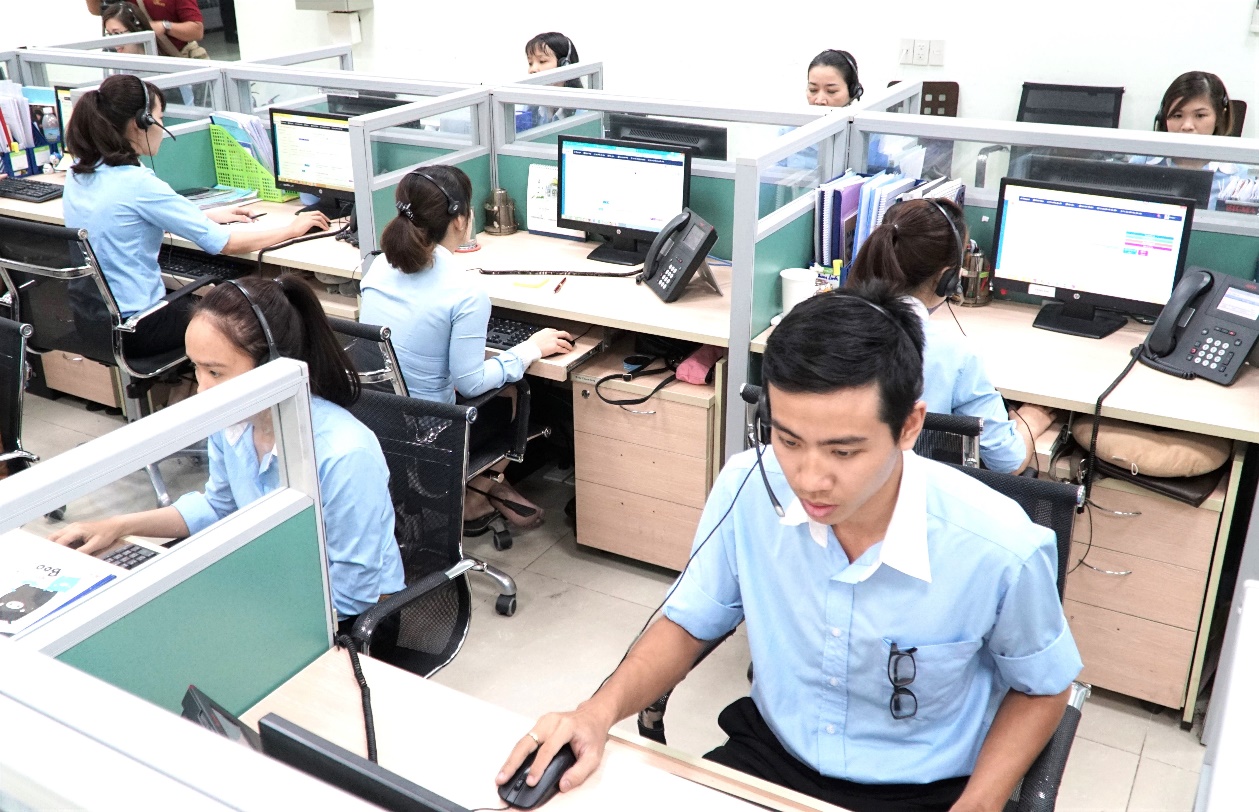 A group of people working at computers Description automatically generated