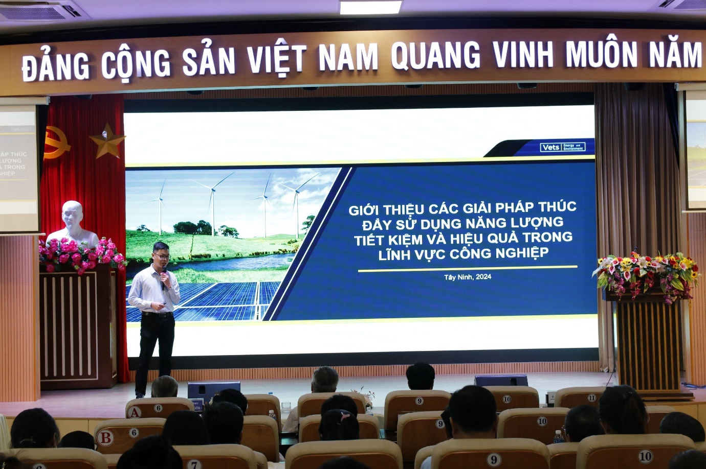 A person standing in front of a large screen  Description automatically generated