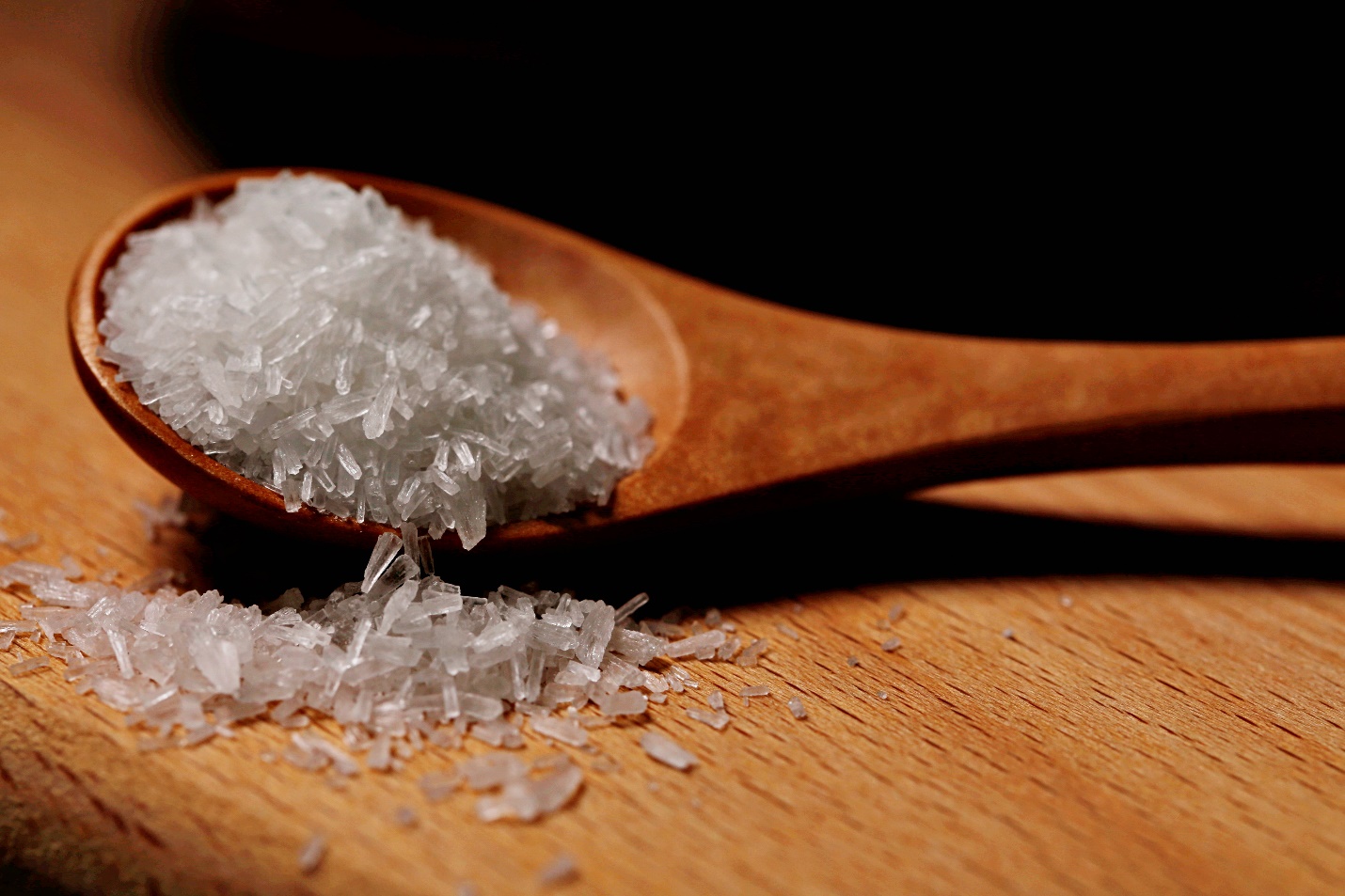 A wooden spoon full of salt Description automatically generated