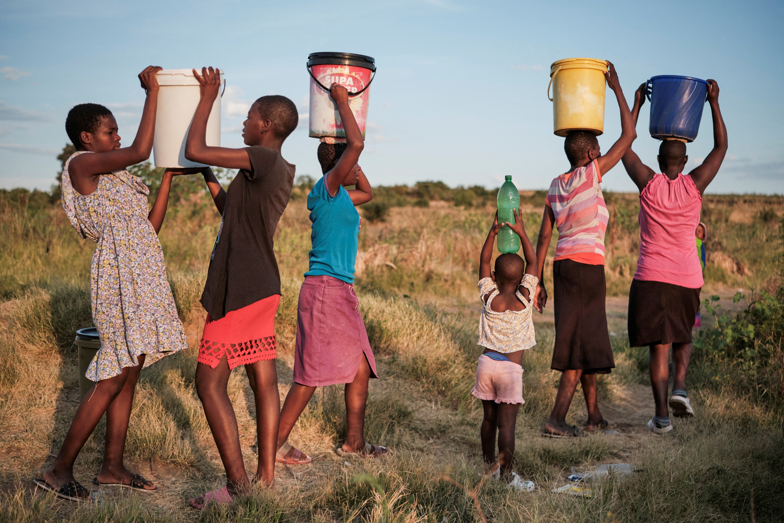 Cư dân thị trấn Pumula East ở Bulawayo - Zimbabwe trở về nhà sau khi lấy nước dùng từ giếng trong đợt nắng nóng và khô hạn đầu tháng 3-2024 Ảnh: REUTERS