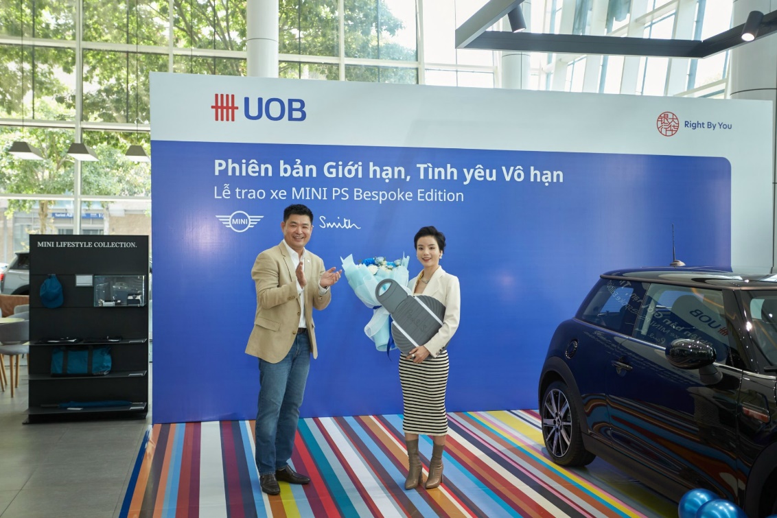 A person and person standing in front of a sign Description automatically generated