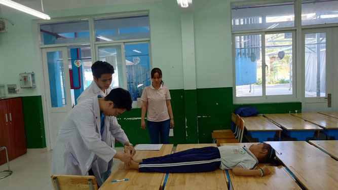 Các bác sĩ tầm soát vẹo cột sống cho học sinh
