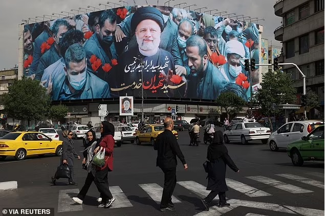 Người d&acirc;n đi ngang qua bảng c&oacute; h&igrave;nh cố Tổng thống Iran Ebrahim Raisi tr&ecirc;n đường phố ở Tehran, Iran, ng&agrave;y 21-5. Ảnh: Reuters