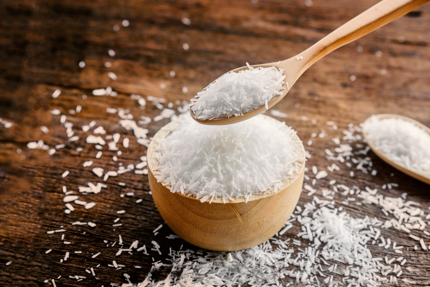 A bowl of coconut flakes with a spoon  Description automatically generated