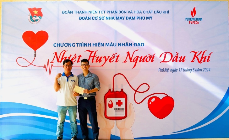 Two men standing in front of a banner Description automatically generated