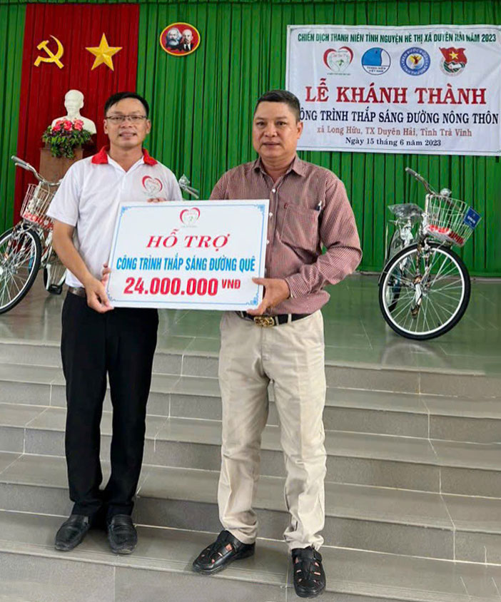 Anh Nguyễn Thanh Tuấn (trái) trao kinh phí hỗ trợ công trình Thắp sáng đường quê tại xã Hữu Long, thị xã Duyên Hải, tỉnh Trà Vinh. (Ảnh do nhân vật cung cấp)