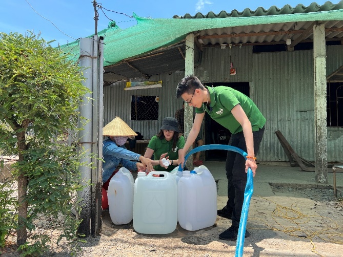 A group of people pouring water into containers  Description automatically generated