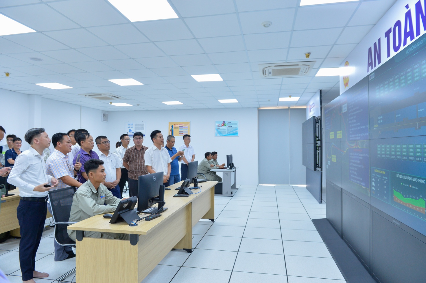 A group of people standing in front of a computer screen Description automatically generated