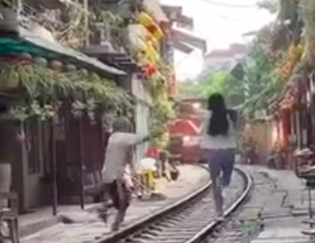 Th&oacute;t tim nữ du kh&aacute;ch lao ra đường ray khi t&agrave;u hỏa đến ở phố c&agrave; ph&ecirc; đường t&agrave;u- Ảnh 1.