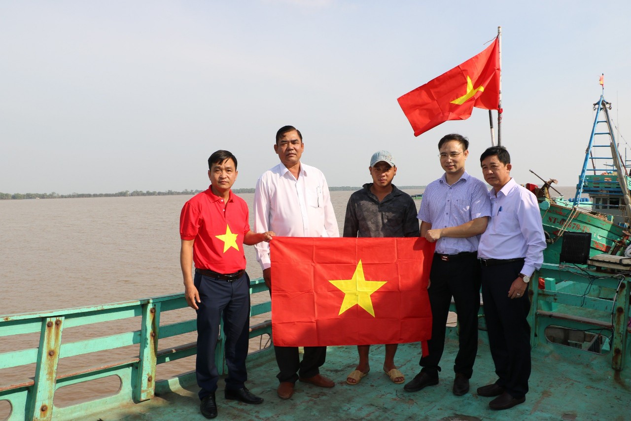 Nhà báo Trần Công Tuấn (bìa trái) trong lần trao cờ Tổ quốc tại tỉnh Sóc TrăngẢnh: PHÚC NGUYÊN