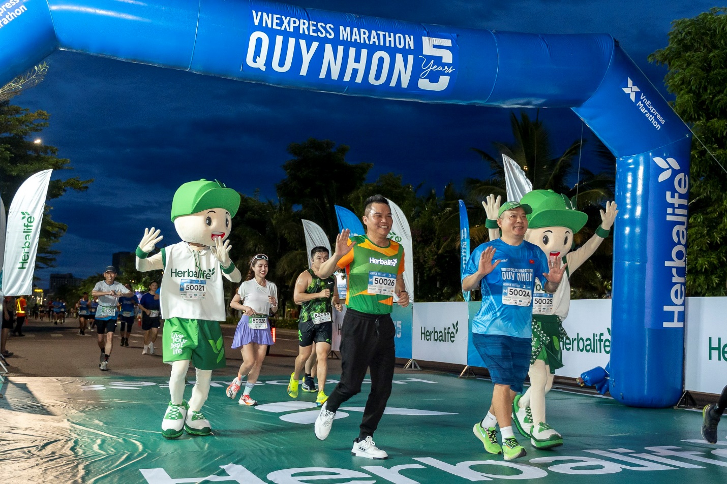 A group of people running under a blue inflatable arch Description automatically generated