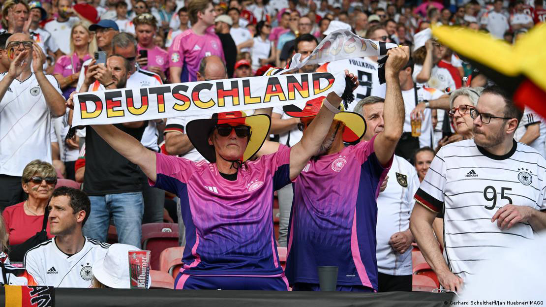 Người h&acirc;m mộ đến s&acirc;n vận động với &aacute;o đấu m&agrave;u hồng c&ugrave;ng chiếc khăn in chữ &ldquo;Deutschland&rdquo;