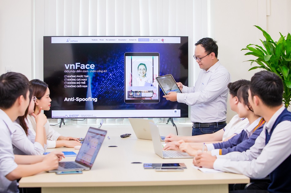 A group of people sitting around a table with laptops Description automatically generated