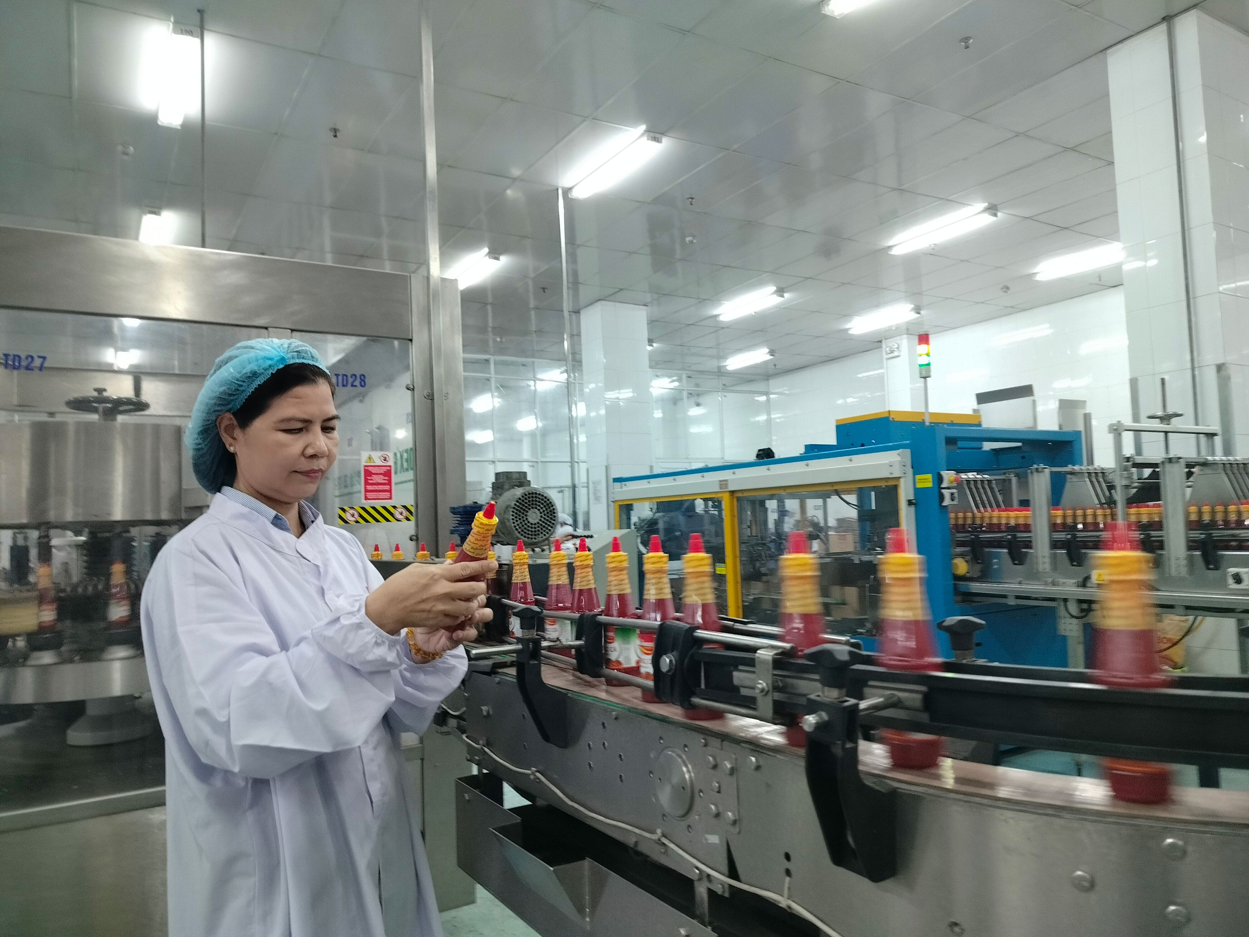 Chị Ph&ugrave;ng Thị Hữu Hạnh kiểm tra d&acirc;y chuyền sản xuất tương ớt. Ảnh: THANH Y&Ecirc;N
