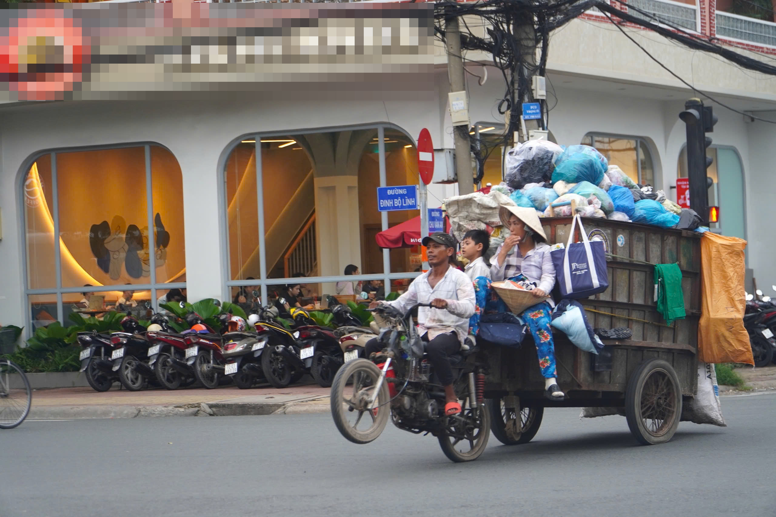 4 th&agrave;nh vi&ecirc;n trong gia đ&igrave;nh ngồi vắt vẻo tr&ecirc;n xe chở r&aacute;c đầy ắp lưu th&ocirc;ng tr&ecirc;n giao lộ Đinh Bộ Lĩnh - Chu Văn An, quận B&igrave;nh Thạnh, TP HCMẢnh: Quốc Anh