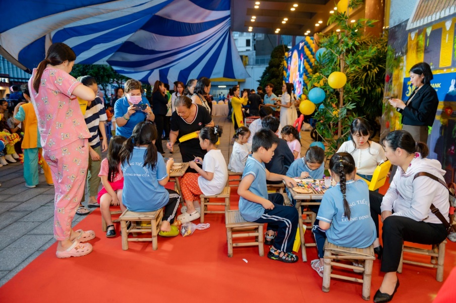 A group of children sitting at tables in a tent Description automatically generated