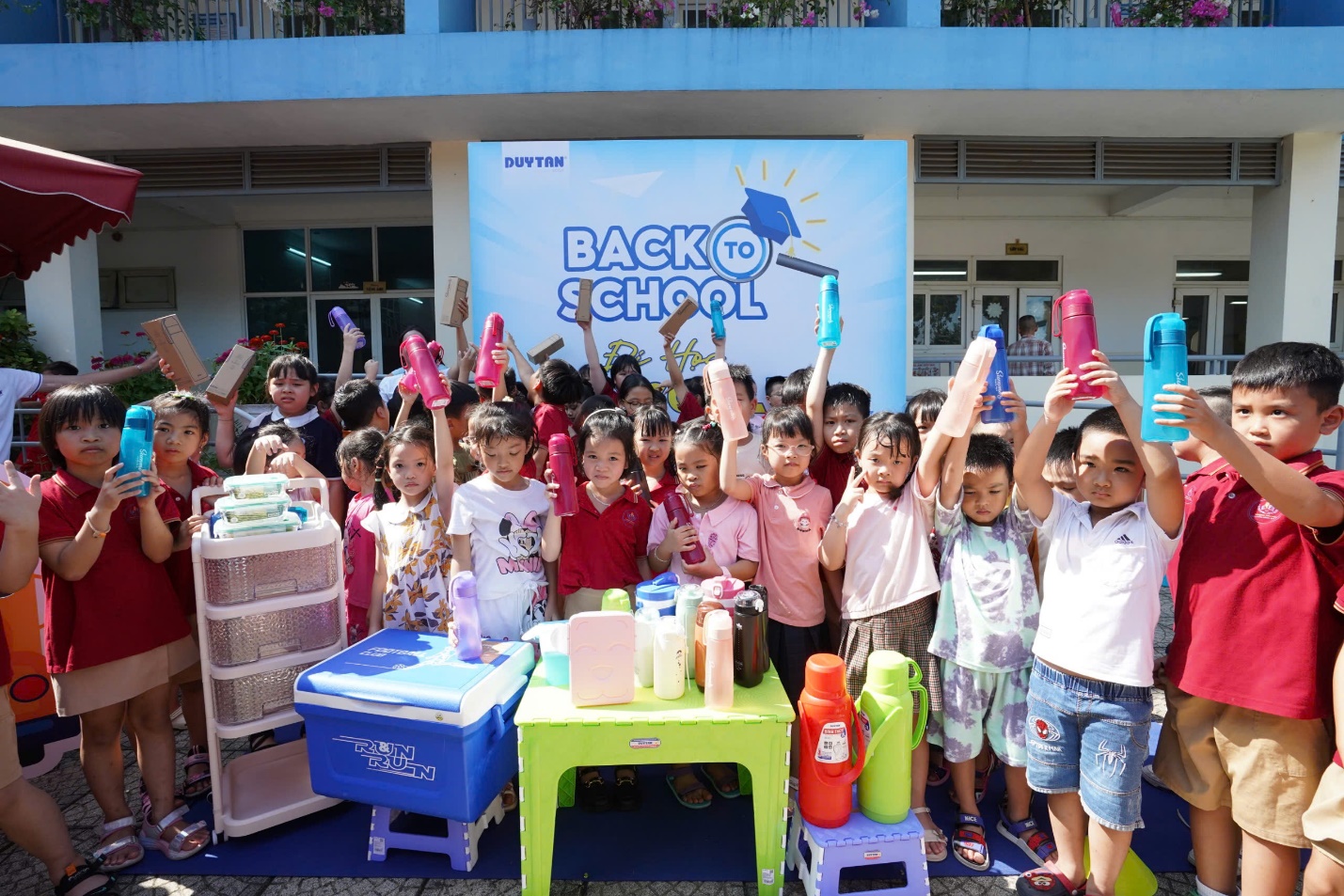 A group of children standing in front of a sign Description automatically generated