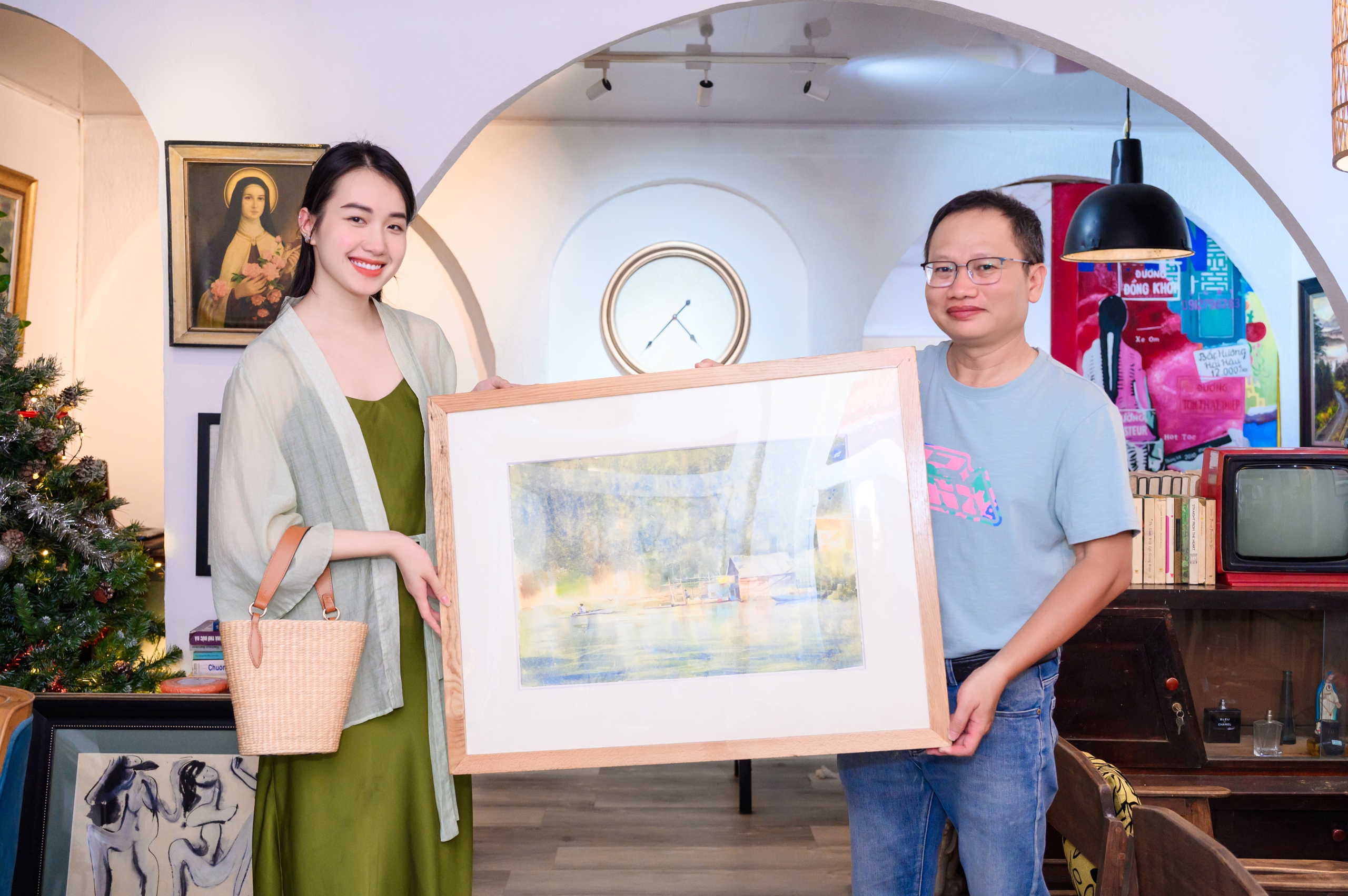 Họa sĩ Phan Anh Thư trao bức tranh &ldquo;Nh&agrave; b&ecirc;n hồ&rdquo; cho nh&agrave; văn Trần Nh&atilde; Thụy. Ảnh: B.T.C