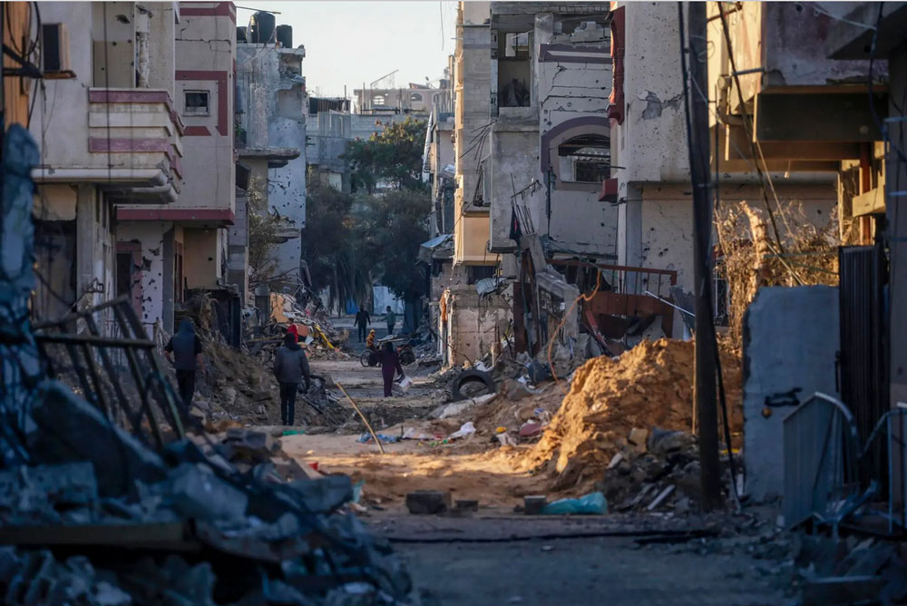Người dân đi ngang qua những ngôi nhà bị phá hủy tại TP Gaza - Dải Gaza hôm 8-2. Ảnh: EFE-EPA