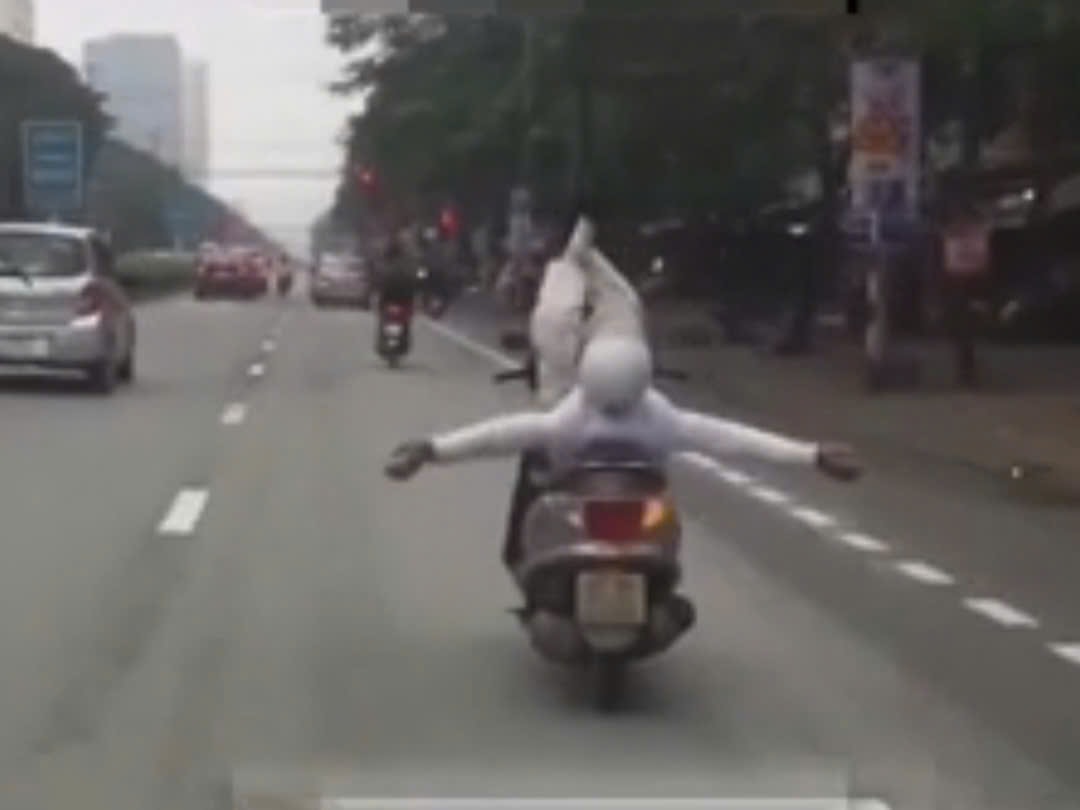 VIDEO: Người đ&agrave;n &ocirc;ng bu&ocirc;ng tay &ldquo;l&agrave;m xiếc&rdquo; với xe m&aacute;y đang chạy tr&ecirc;n phố- Ảnh 1.