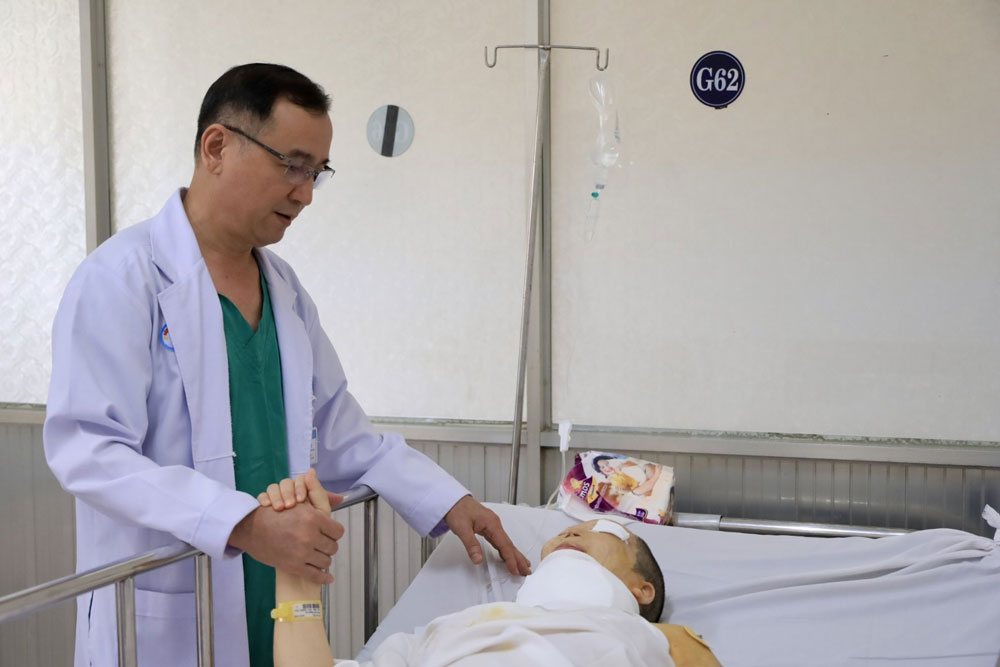 TS-BS Ng&ocirc; Đức Hiệp, Trưởng Khoa Phỏng - Tạo h&igrave;nh Bệnh viện Chợ Rẫy, thăm kh&aacute;m cho bệnh nh&acirc;n. Ảnh: NGỌC QU&Yacute;