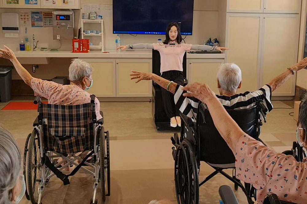 Cư d&acirc;n tại một viện dưỡng l&atilde;o ở khu vực Punggol (Singapore) tương t&aacute;c với robot Dexie. Ảnh: THE STRAITS TIMES