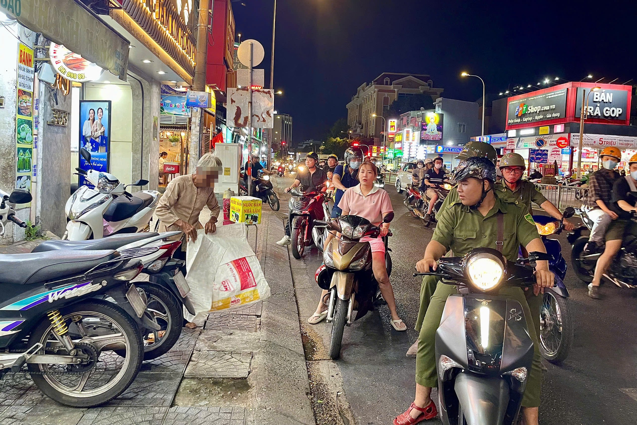 Cảnh trên đường Bạch Đằng, quận Bình Thạnh. Lực lượng chức năng nhắc nhở, yêu cầu cụ bà xin tiền di chuyển đi nơi khác Ảnh: ANH VŨ