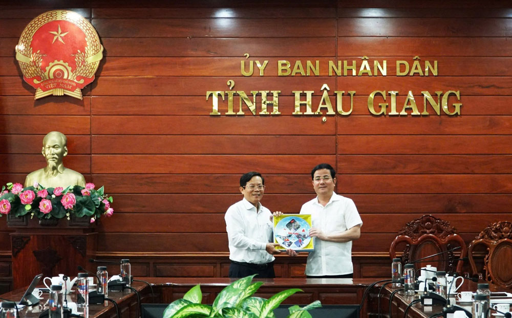 Tổng Biên tập Báo Người Lao Động Tô Đình Tuân (trái) trao quà lưu niệm từ chương trình “Tự hào cờ Tổ quốc” cho Chủ tịch UBND tỉnh Hậu Giang Trần Văn Huyến. Ảnh: VÕ DƯƠNG