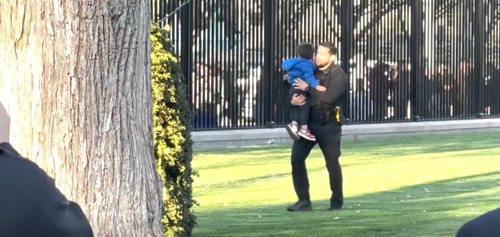 Secret Service agent holding a child who slipped through White House fencing