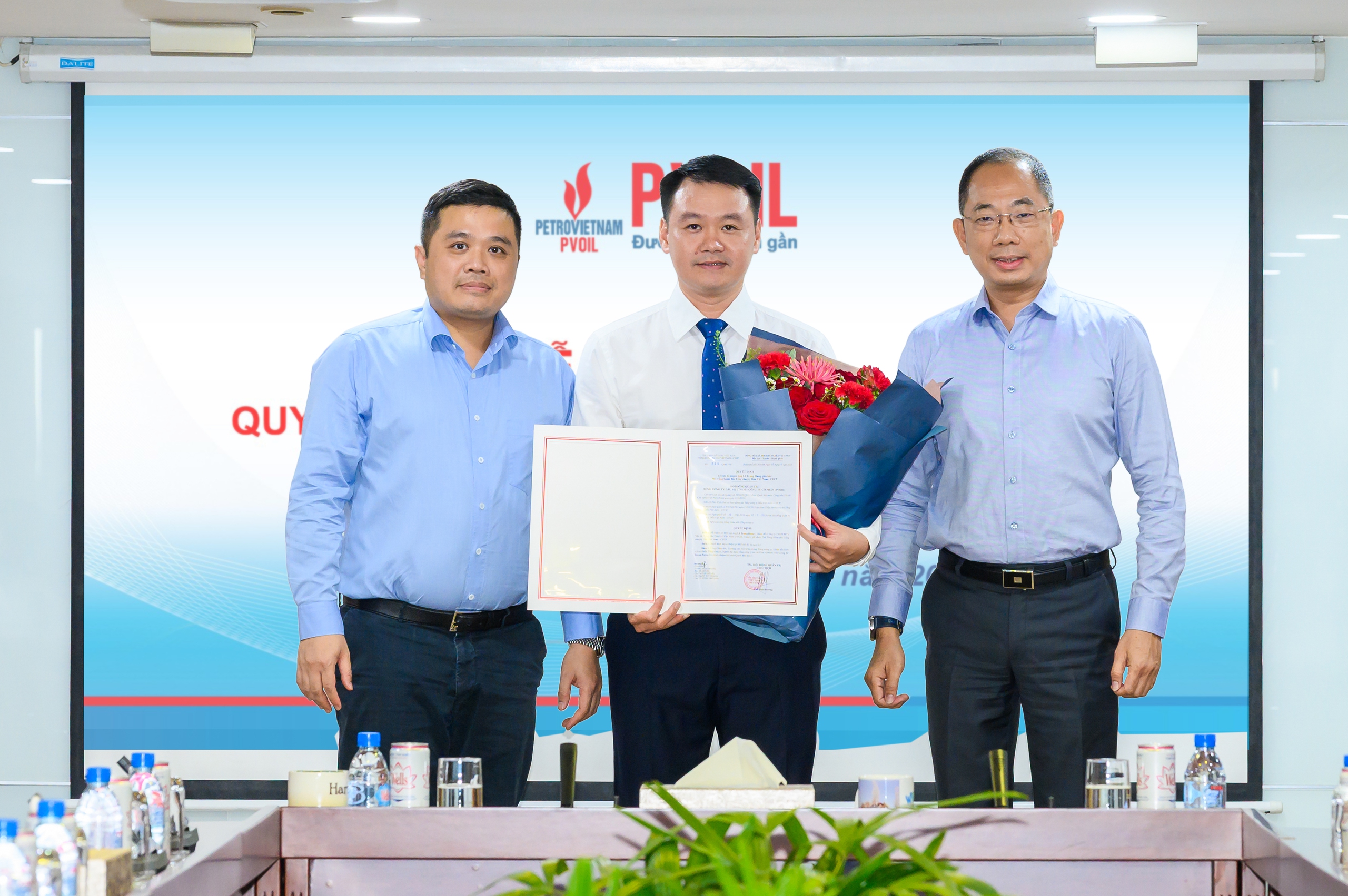Ông Cao Hoài Dương - Bí thư Đảng ủy, Chủ tịch HĐQT Tổng công ty (bên phải) và ông Nguyễn Đăng Trình - Phó Bí thư Đảng ủy, Tổng Giám đốc Tổng công ty (bên trái) trao quyết định và tặng hoa chúc mừng ông Lê Trung Hưng