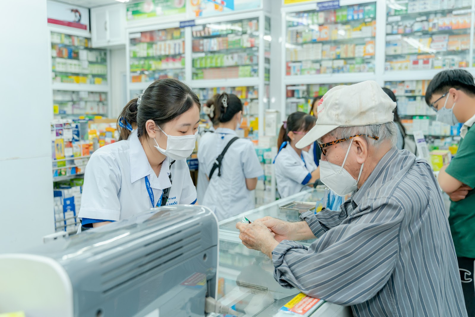 A person wearing a mask and a white cap in a pharmacy  AI-generated content may be incorrect.