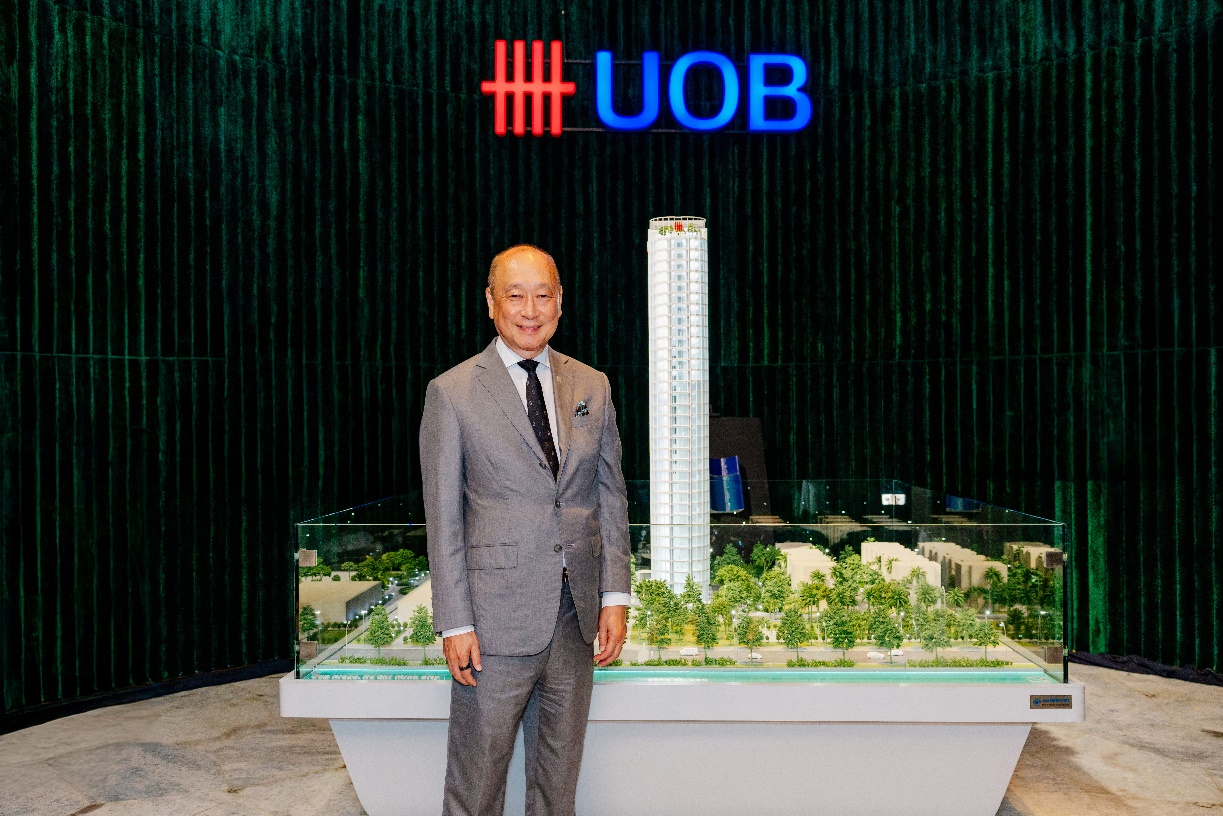 A person in a suit standing in front of a model of a tall building AI-generated content may be incorrect.