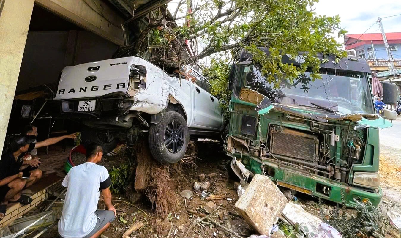 Xe tải mất l&aacute;i t&ocirc;ng tr&uacute;ng &ocirc; t&ocirc; đậu b&ecirc;n đường, bật gốc c&acirc;y lộc vừng - Ảnh 1.