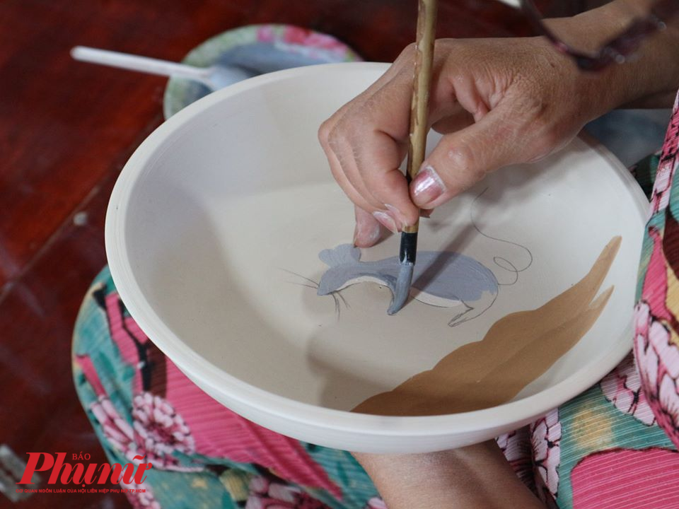 Nghệ nh&acirc;n gốm thực hiện c&ocirc;ng đoạn chấm men vẽ hoa văn.