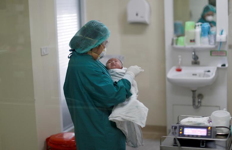 Nữ y t&aacute; đang bế một em b&eacute; 1 th&aacute;ng tuổi mắc COVID-19 (cũng l&agrave; bệnh nh&acirc;n nhỏ tuổi nhất Th&aacute;i Lan)