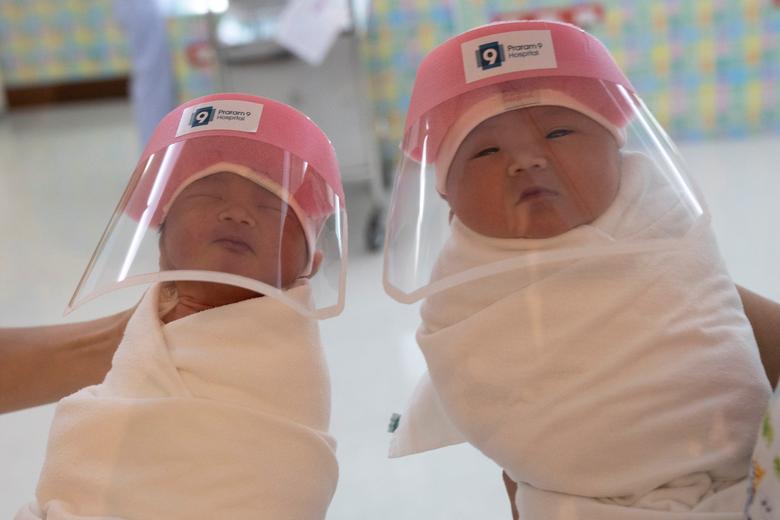 Hai em b&eacute; ch&agrave;o đời h&ocirc;m 9/4 tại bệnh viện ở Băng Cốc, Th&aacute;i Lan được đeo mũ bảo hộ để tr&aacute;nh l&acirc;y nhiễm dịch bệnh.