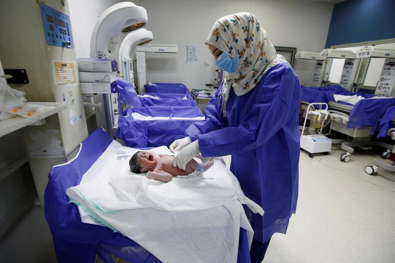 Nữ y t&aacute; trong một bệnh viện ở Najab, Iraq đeo khẩu trang, mang găng tay cẩn thận khi chăm s&oacute;c cho một em b&eacute; vừa ch&agrave;o đời.