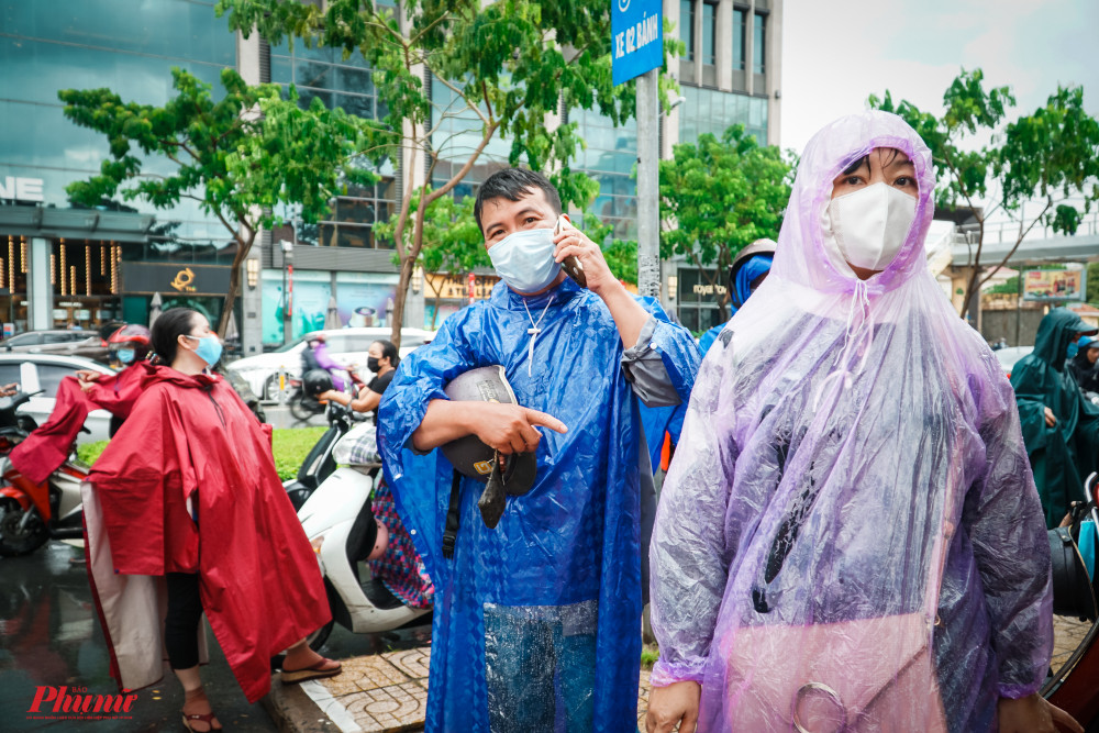 Nhiều phụ huynh đội mưa đứng tr&ocirc;ng ng&oacute;ng con từ ph&iacute;a ngo&agrave;i cổng trường