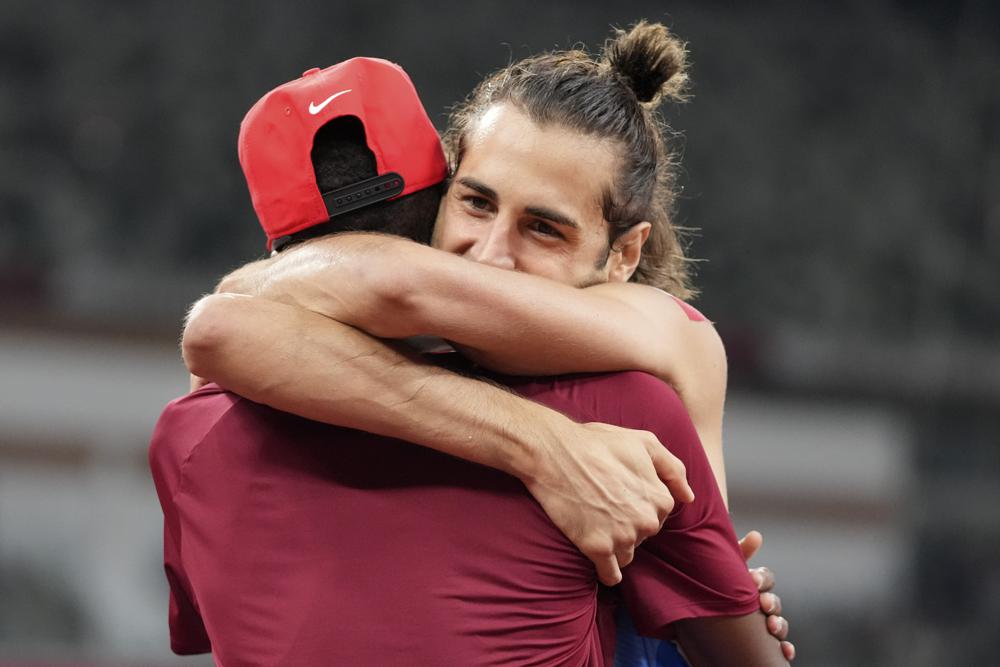 Gianmarco Tamberi (&Yacute;) &ocirc;m lấy người c&ugrave;ng gi&agrave;nh huy chương v&agrave;ng Mutaz Barshim (Qatar) với m&igrave;nh sau trận chung kết nhảy cao nam tại Thế vận hội m&ugrave;a h&egrave; 2020 ở Tokyo. Ảnh: AP