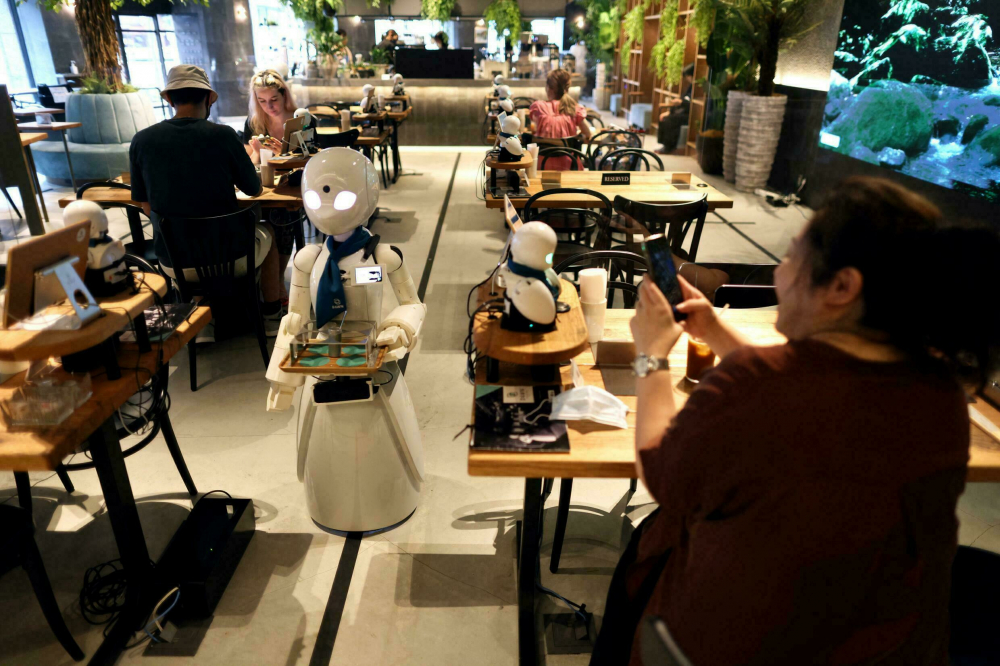 Khoảng 20 robot nhỏ với đ&ocirc;i mắt h&igrave;nh quả hạnh nh&acirc;n được bố tr&iacute; trong qu&aacute;n c&agrave; ph&ecirc; - Ảnh: AFP