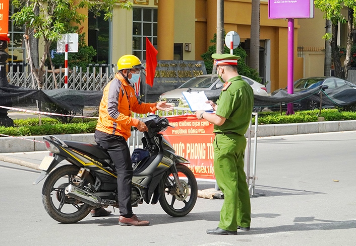 Lực lượng cảnh s&aacute;t khu vực phường Đồng Ph&uacute; TP. Đồng Hới kiểm tra giấy đi đường của người d&acirc;n khi qua chốt. Ảnh: N.H