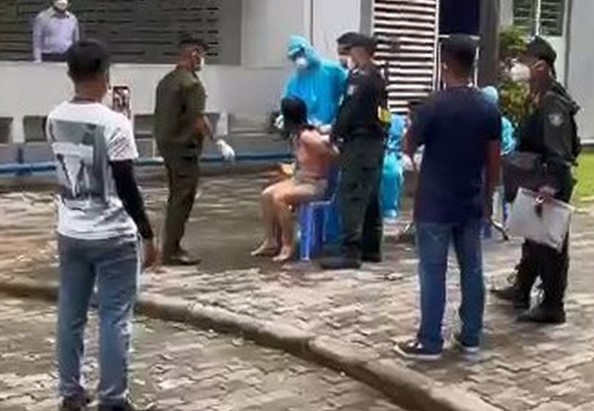 Chị L. bị lực lượng chức năng phường Vĩnh Ph&uacute; ph&aacute; cửa căn hộ, khống chế đưa xuống s&acirc;n chung cư để test COVID-19. Ảnh cắt từ clip.