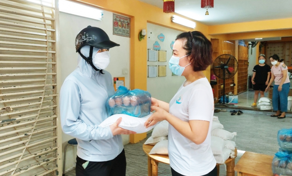 Đại diện Hiệp hội Mầm non tư thục H&agrave; Nội (b&igrave;a phải) hỗ trợ nhu yếu phẩm cho gi&aacute;o vi&ecirc;n mầm non trong đợt H&agrave; Nội thực hiện gi&atilde;n c&aacute;ch
