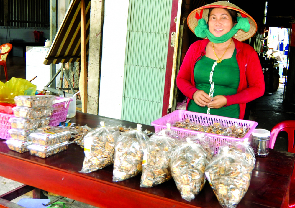 Chị Ng&ocirc; Thị Hồng Nhung vừa l&agrave;m vừa b&aacute;n kẹo ngay trước nh&agrave;